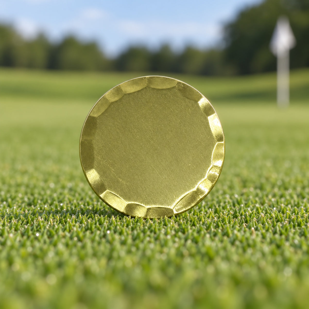 Blank 38 mm gold golf ball marker with a bevelled edge, standing on a putting green